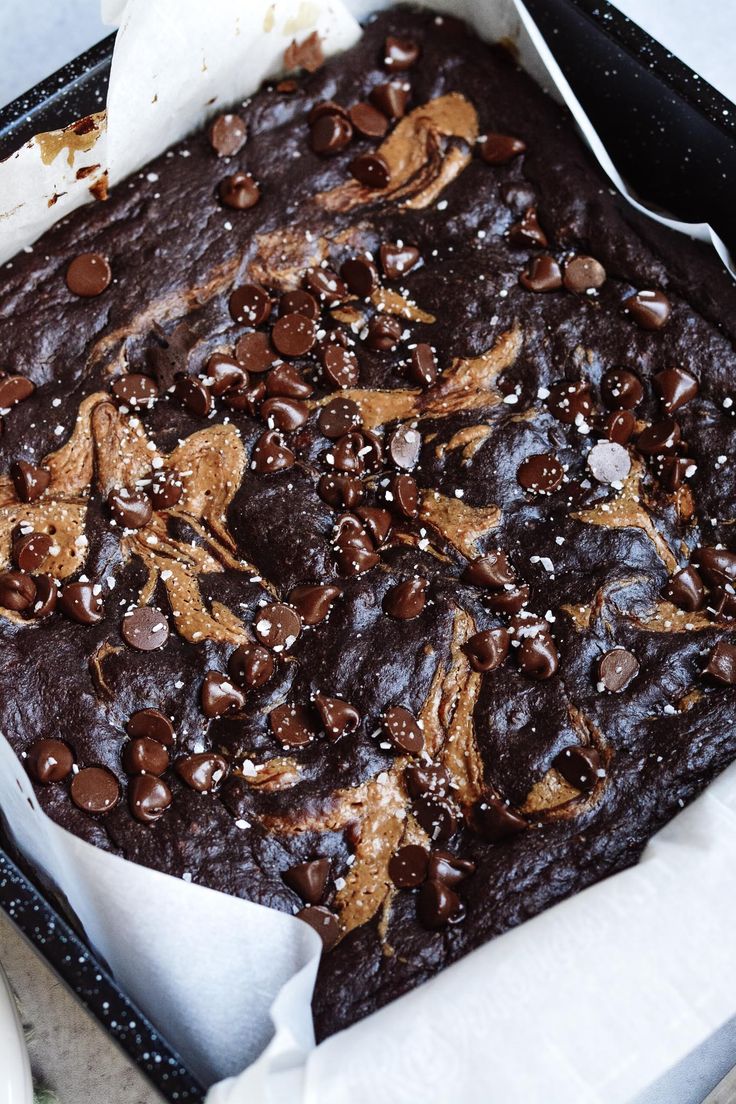 a chocolate cake in a black pan with white napkins and spoon on the side