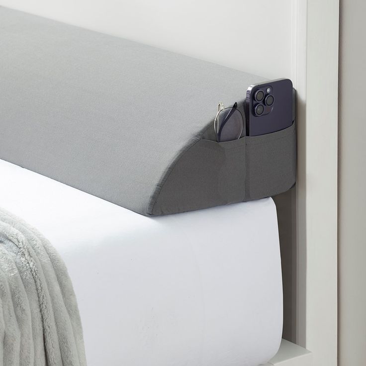 a close up of a bed with a pillow and eyeglasses on the headboard