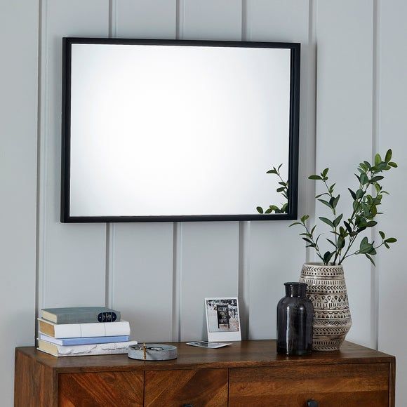 a wooden dresser topped with a mirror next to a plant