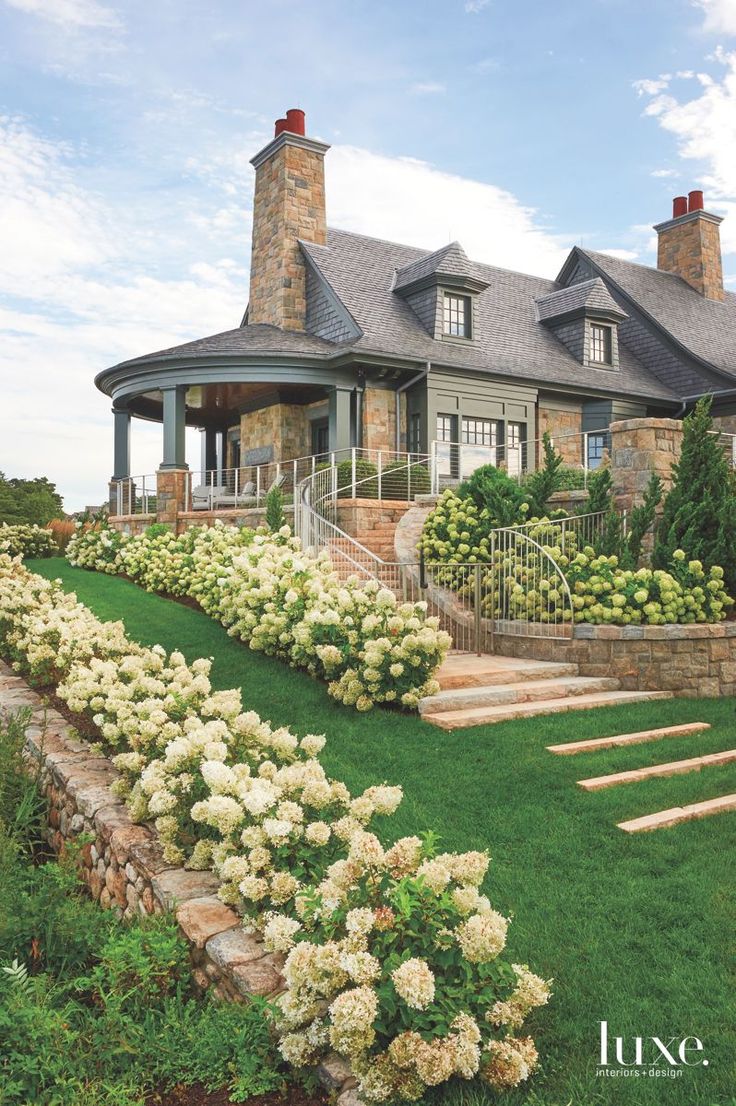 a large house with steps leading up to it's front door and flowers in the foreground