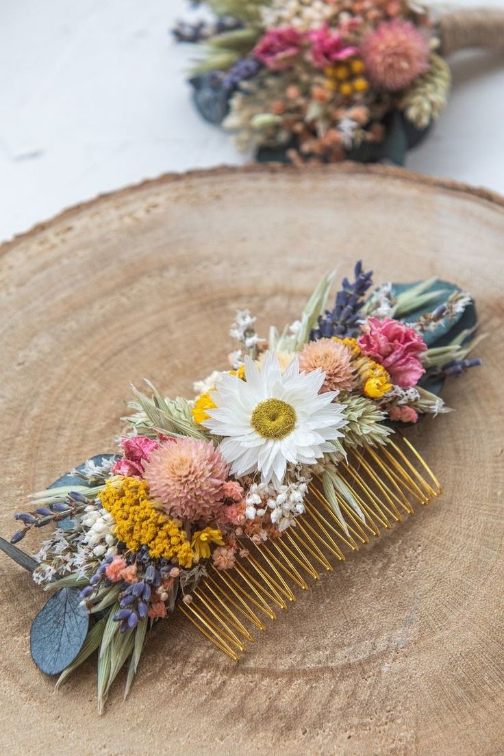 a comb with flowers on it sitting on top of a wooden table next to another piece of wood