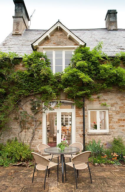 an outdoor table and chairs in front of a brick building with ivy growing on it