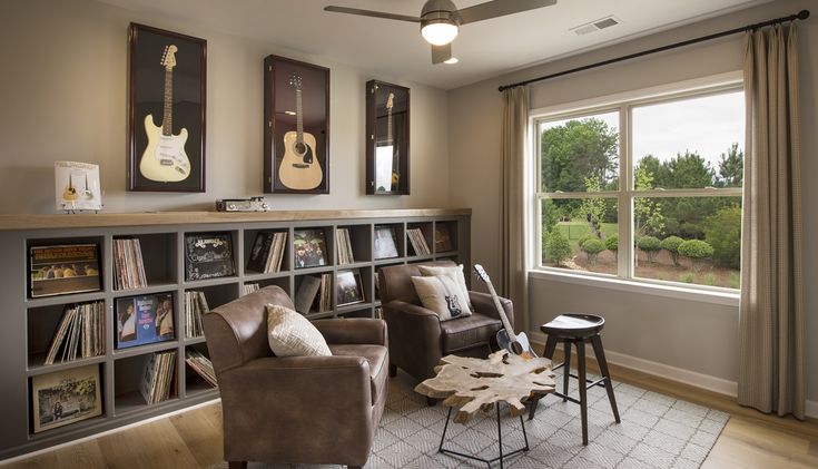 a living room filled with furniture next to a window covered in curtains and bookshelves