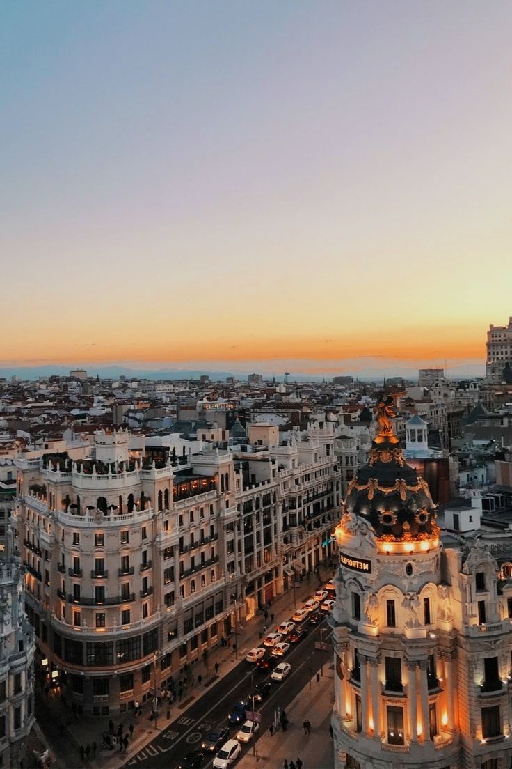 an aerial view of a city at sunset with tall buildings in the foreground and cars on the street below