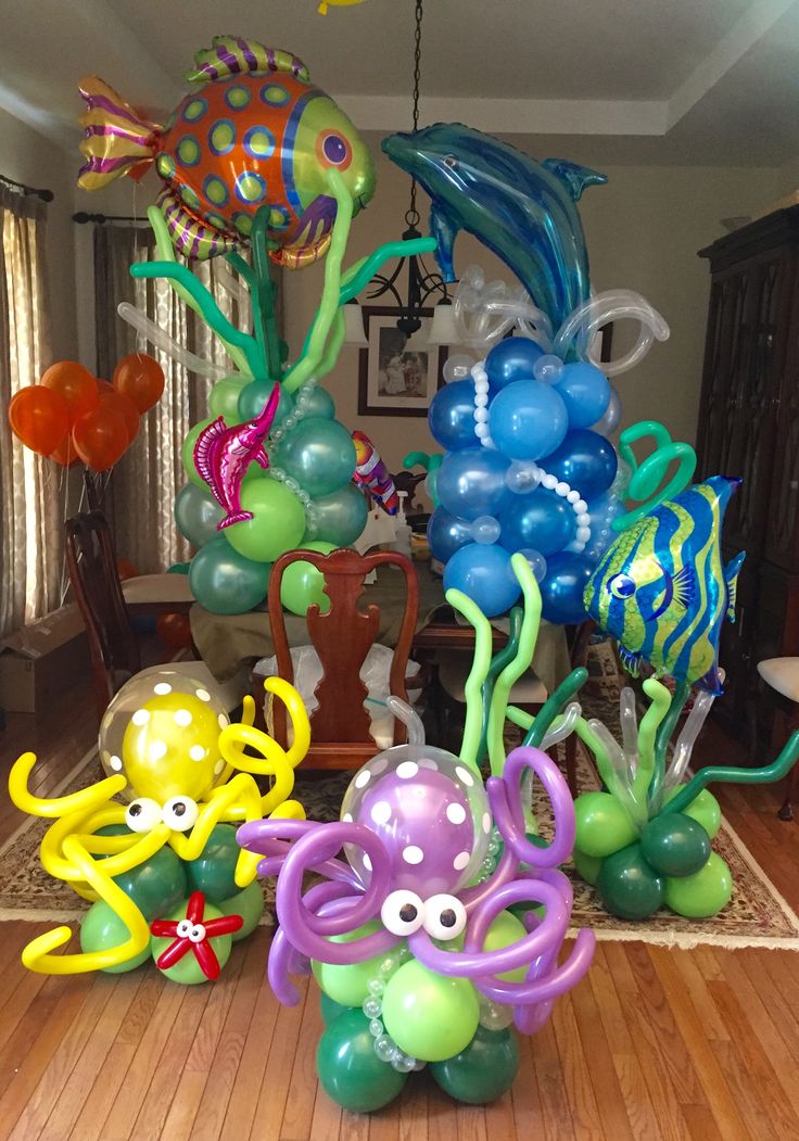 an assortment of balloons in the shape of sea animals and fish on a wooden floor