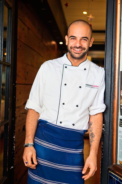 a man in a chef's uniform standing next to an open door with his hands on his hips