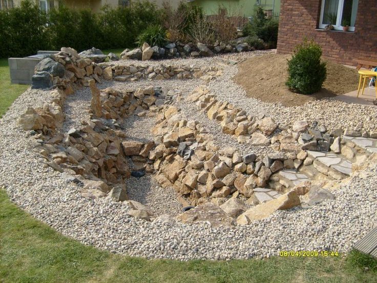 an outdoor area with rocks and gravel in the middle, next to a yellow bench