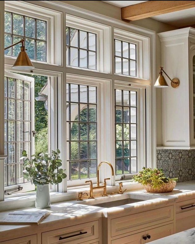 an instagramted photo of a kitchen with white cabinets and large windows in the center