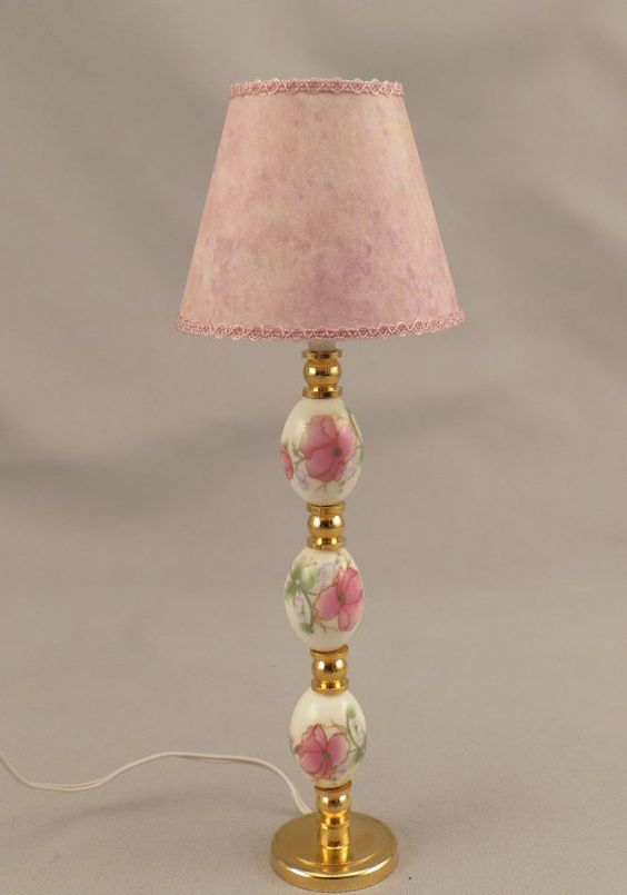 a pink lamp with flowers on it and a cord plugged into the light fixture