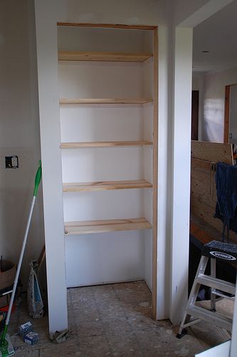 an empty room with some shelves and tools in the foreground on the right side