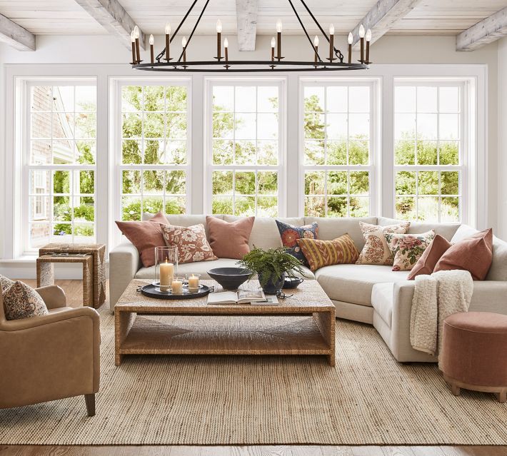 a living room filled with lots of furniture next to two large windows and a chandelier hanging from the ceiling