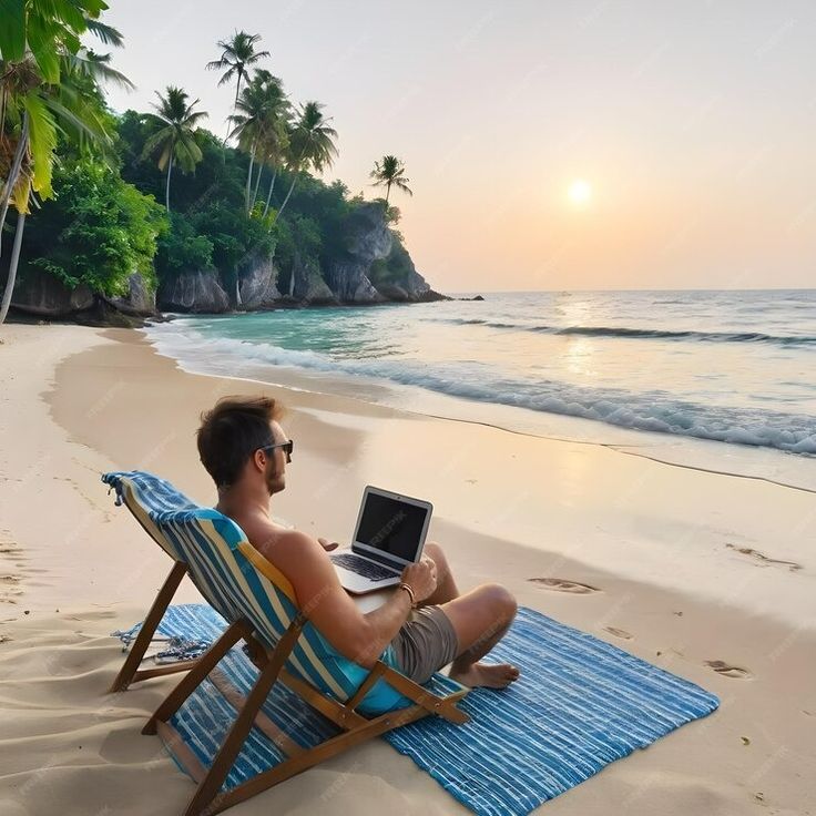 a man sitting in a chair on top of a beach using a lap top computer