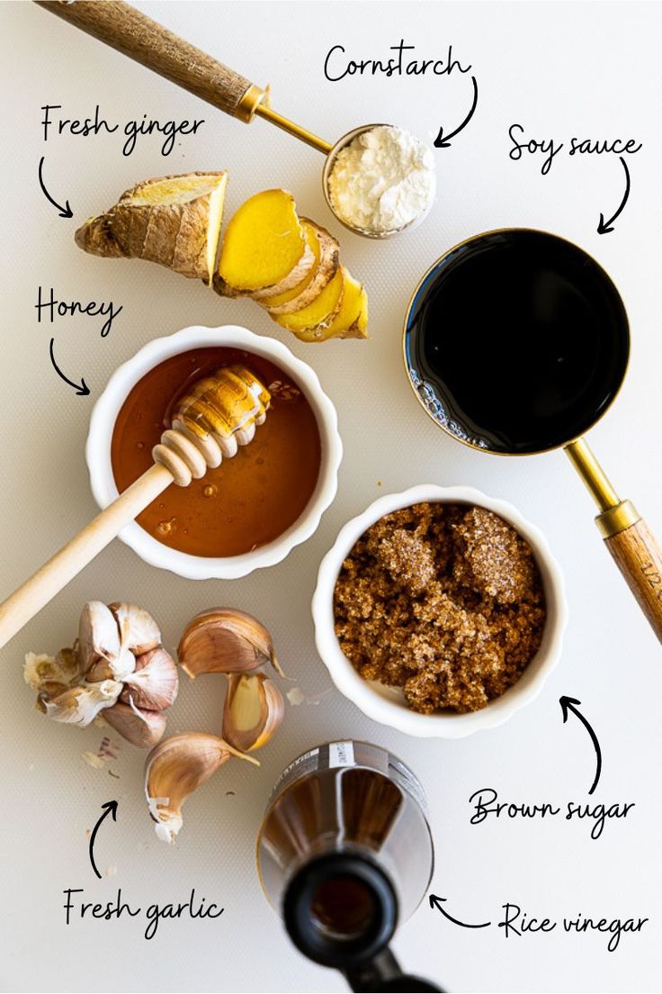 ingredients to make an ice cream recipe laid out on a white counter top, including honey, ginger, garlic, and more