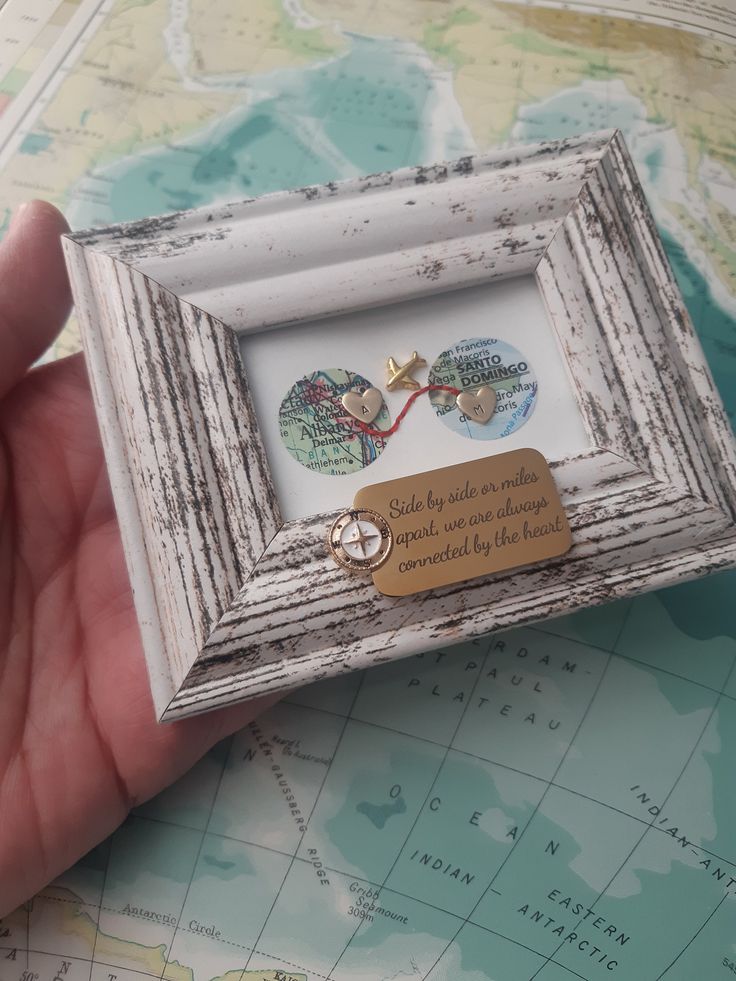 a person holding a small white frame with two buttons in it on top of a map