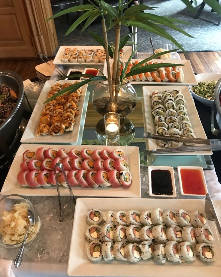 a table filled with lots of different types of sushi and other foods on plates