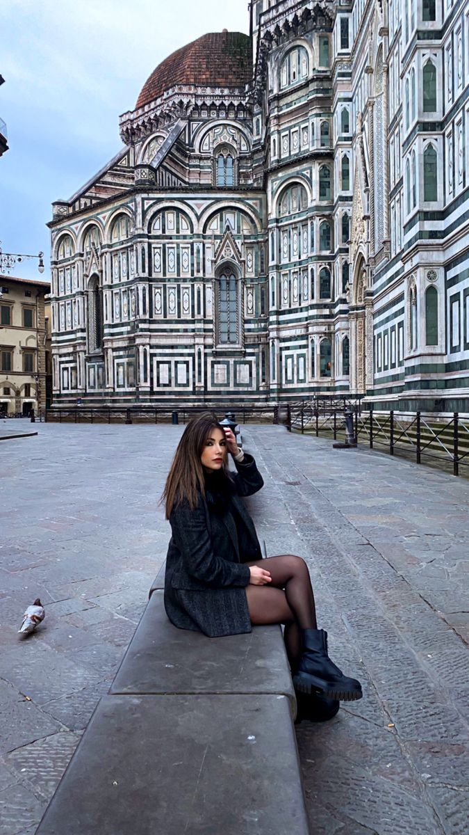 a woman sitting on top of a cement bench in front of a large white building