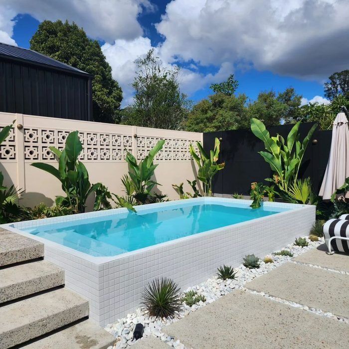 an empty swimming pool in the middle of a backyard with steps leading up to it