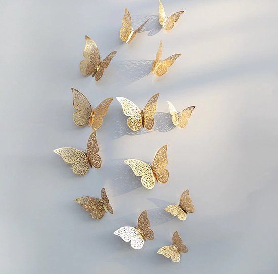 a group of gold and white butterflies on a gray surface with shadows coming from them