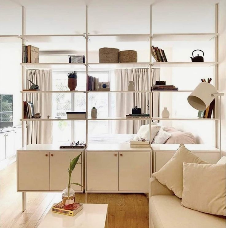 a living room filled with furniture and bookshelves next to a white couch in front of a window