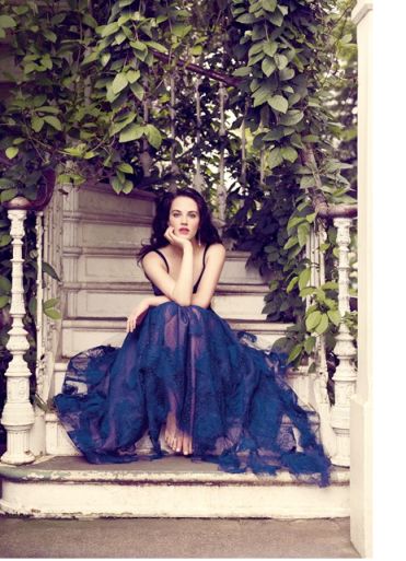 a woman in a blue dress sitting on a porch