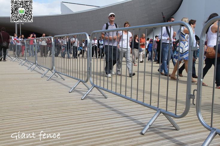 a crowd of people standing next to a metal fence