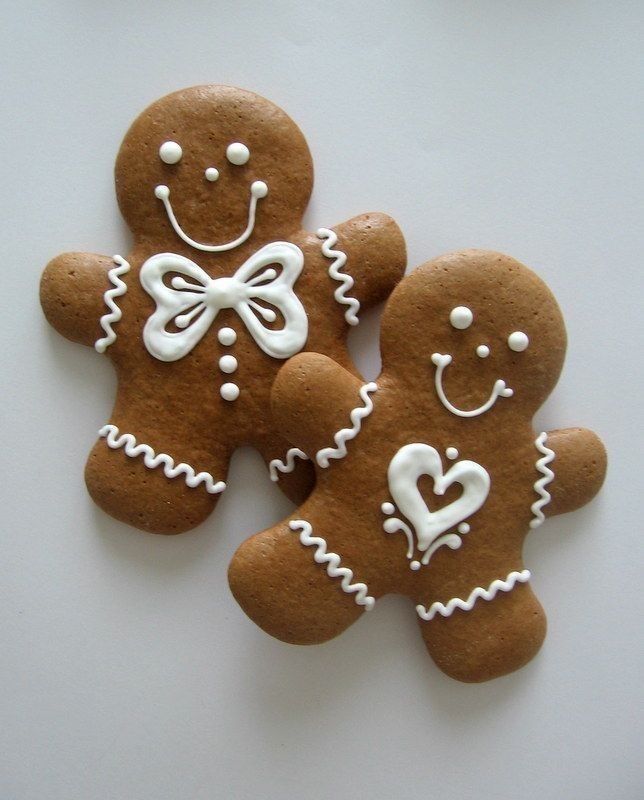 three gingerbread cookies with white icing and bows