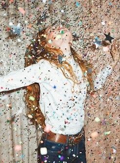 a woman standing in front of a curtain covered in confetti