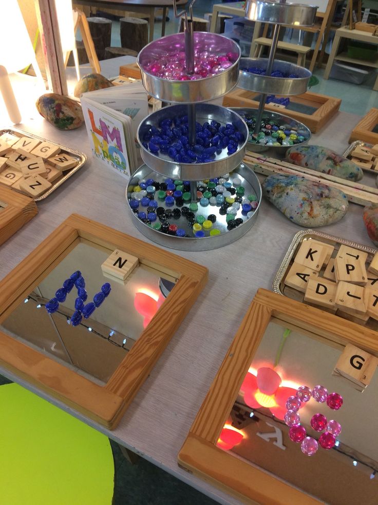 a table topped with lots of different types of beads and wooden letters on trays