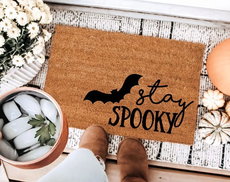 someone is standing in front of a door mat that says stay spooky