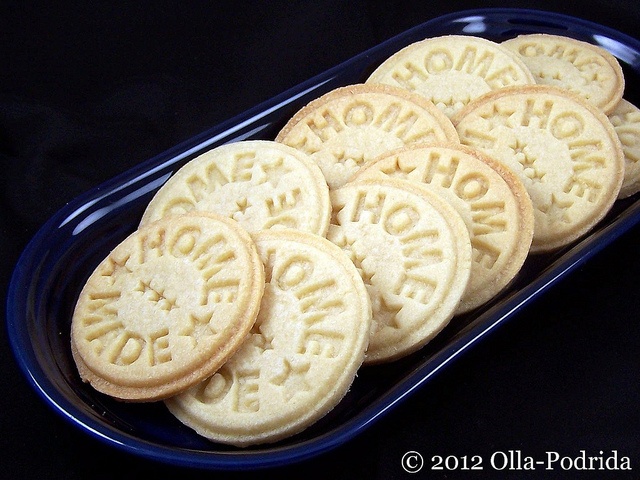 several cookies are arranged in a blue tray on a black tablecloth with words written across the top