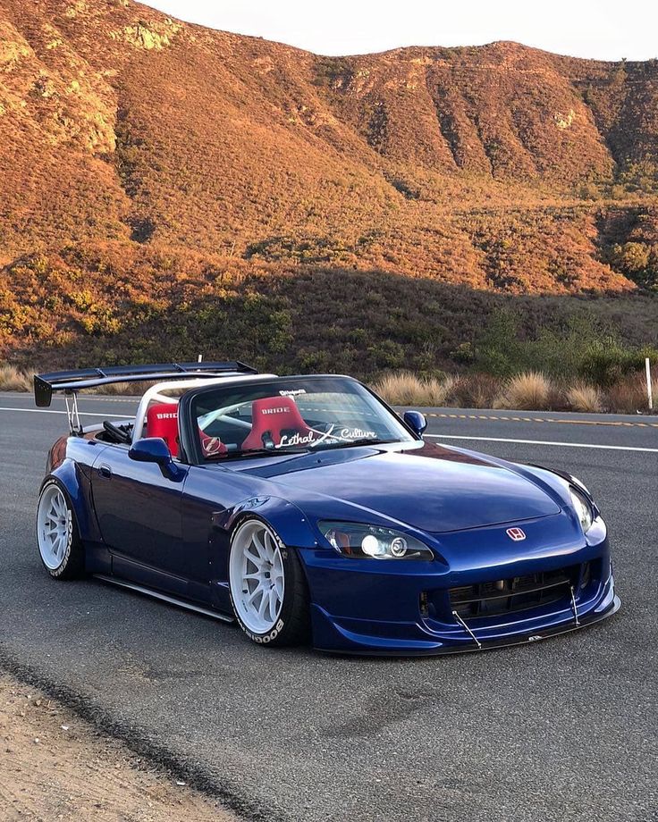 a blue sports car parked in front of a mountain