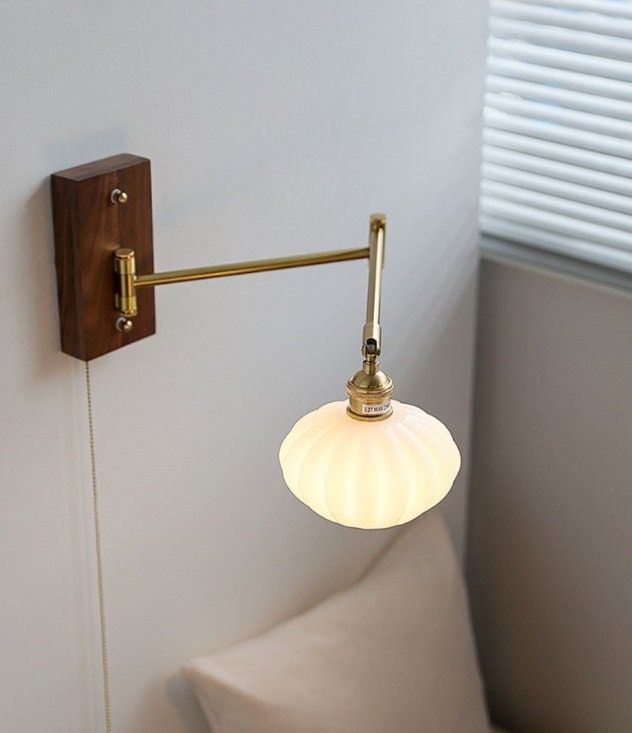 a wall light that is on the side of a white wall next to a pillow