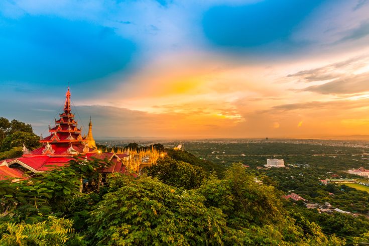 a red and yellow building sitting on top of a lush green hillside