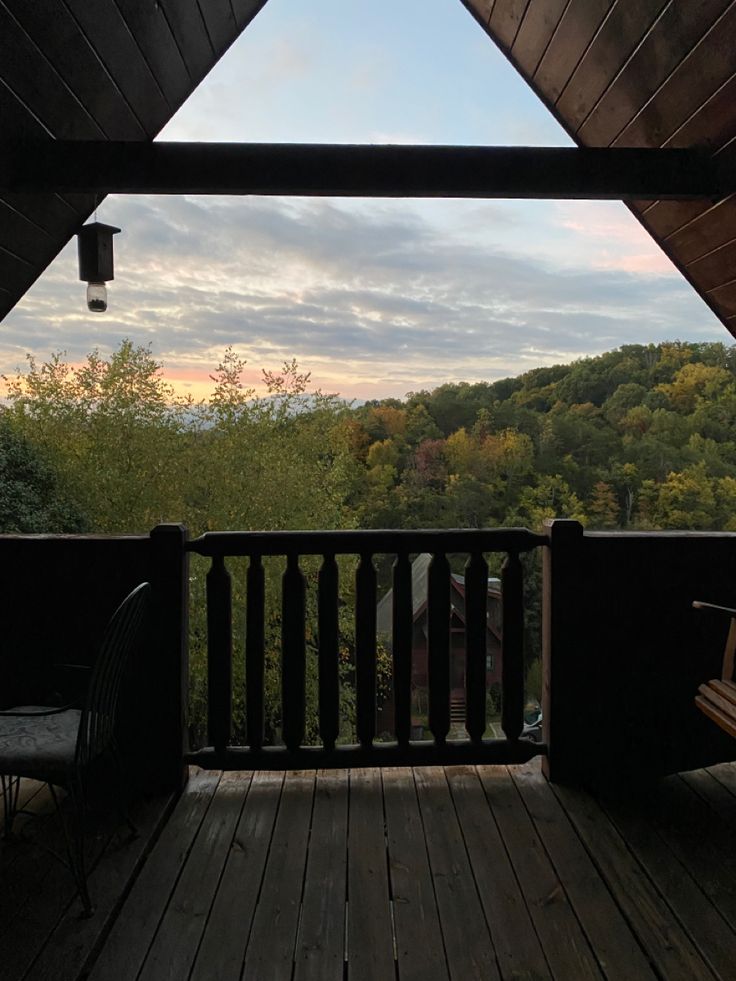 a wooden deck with two chairs on it and a view of the mountains in the distance