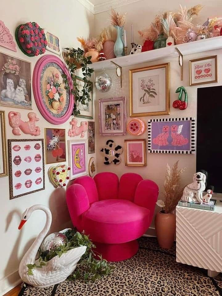 a pink chair sitting in front of a tv on top of a wooden dresser next to a wall covered with pictures