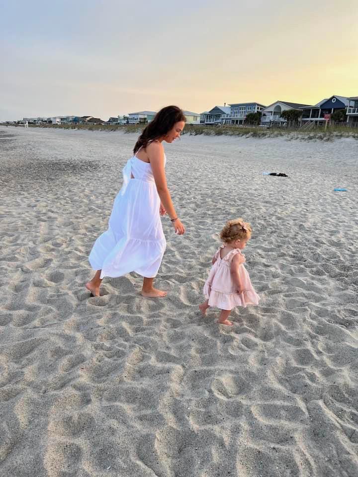 a mother and daughter walking on the beach