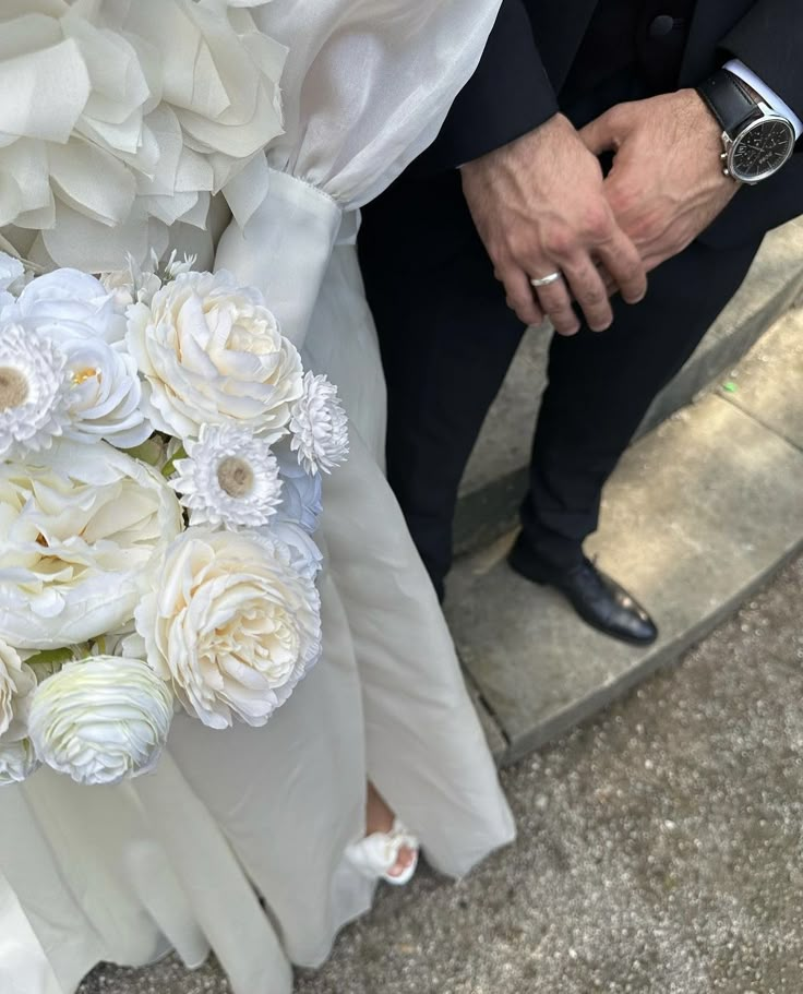 a bride and groom holding hands with white flowers