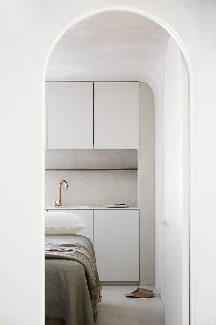 an arch leading into a bedroom with a bed and cupboards in the corner,