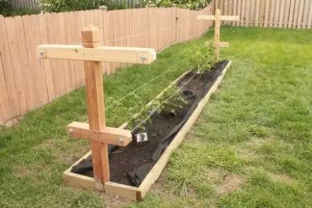 a wooden cross sitting in the middle of a garden with plants growing out of it