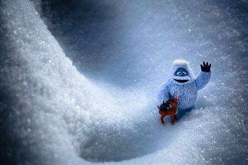 a small toy is standing in the snow with his arms out and legs spread wide