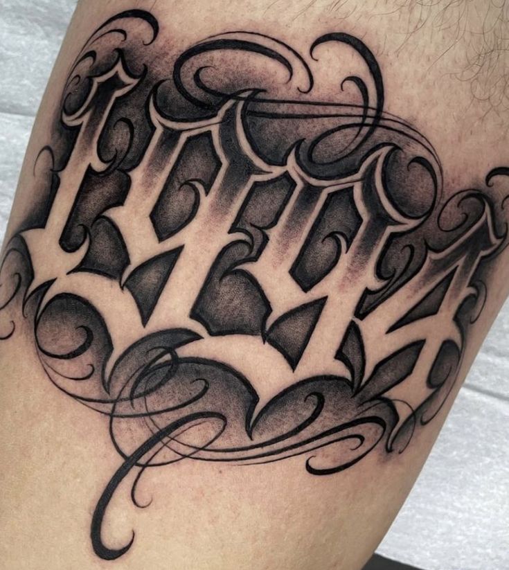 a black and white tattoo design on the leg, with letters that spell it out