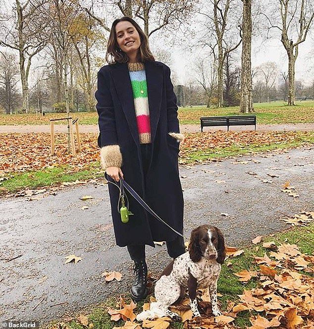 a woman is walking her dog on a leash in the park with leaves around her