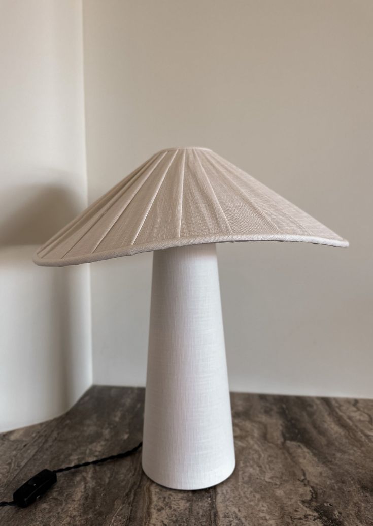 a white lamp sitting on top of a wooden table next to a black corded phone