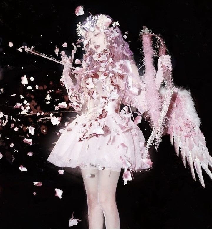 a woman dressed in pink and white holding an umbrella with petals all over her body