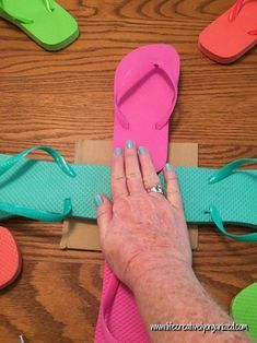 a woman's hand is on the top of several pairs of flip flops