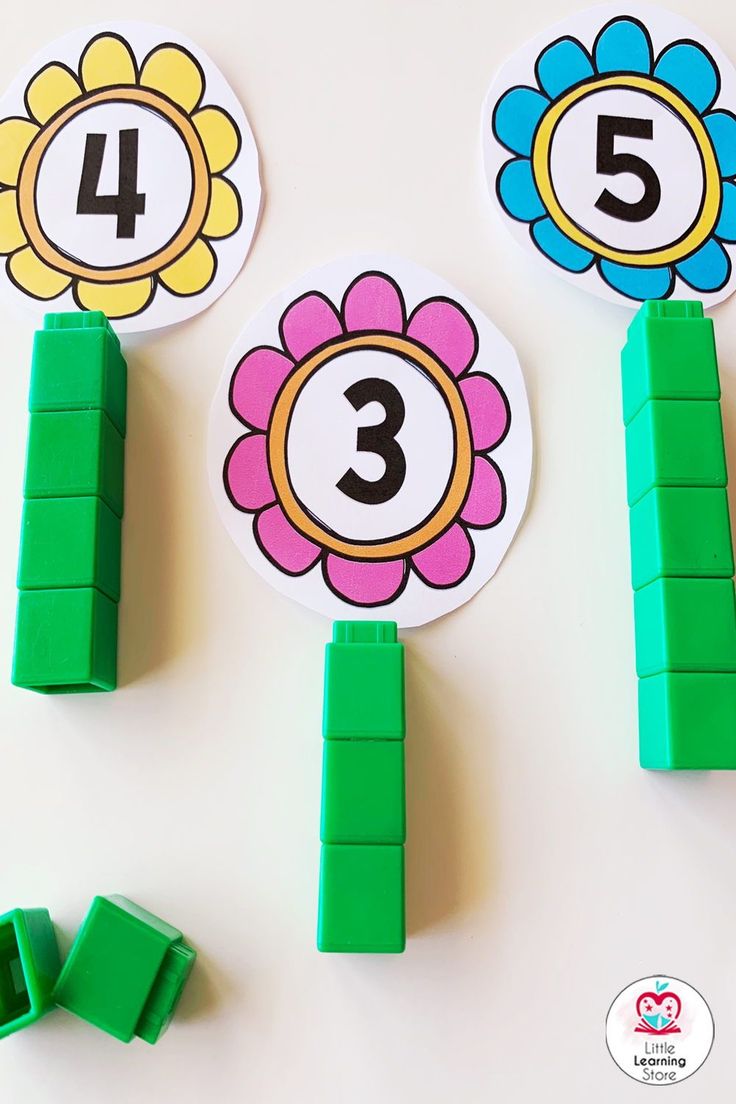 three flowers with numbers on them sitting in front of green pegs that spell out the number