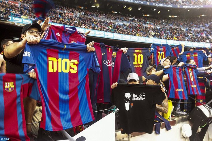 a group of men holding up shirts in front of a crowd at a soccer game