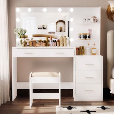 a white vanity with lights on it next to a bed and a chair in a room