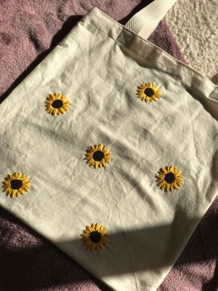 a white bag with yellow sunflowers on it sitting on a pink blanket next to a pair of scissors