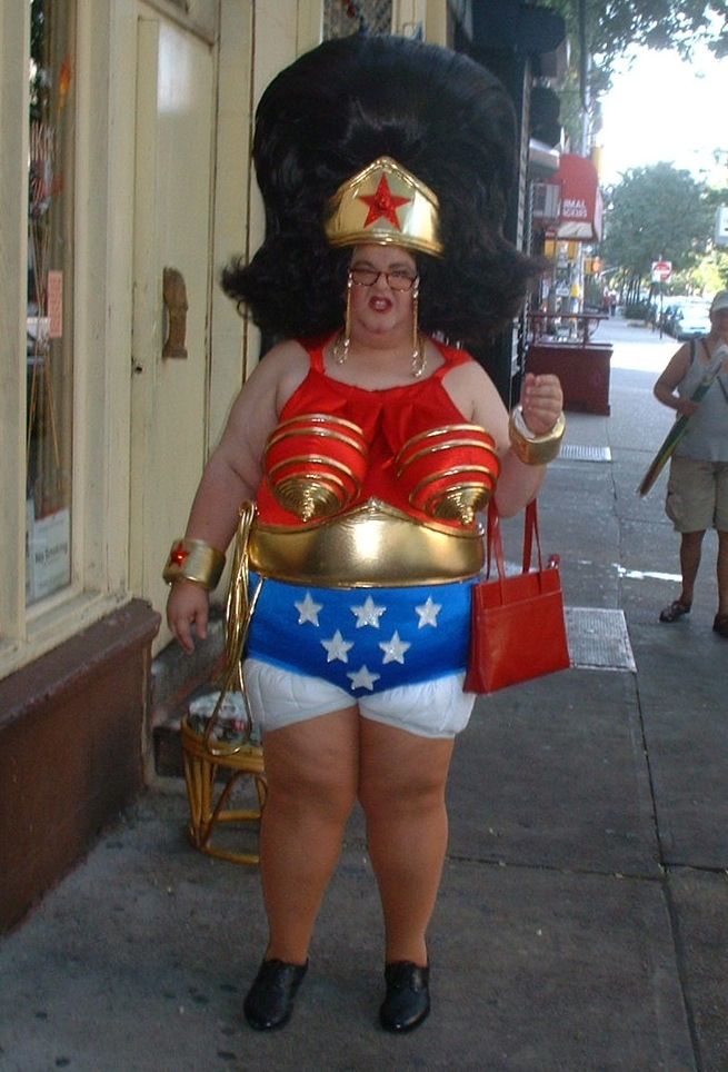 a woman dressed in wonder costume walking down the street with her purse on her hip